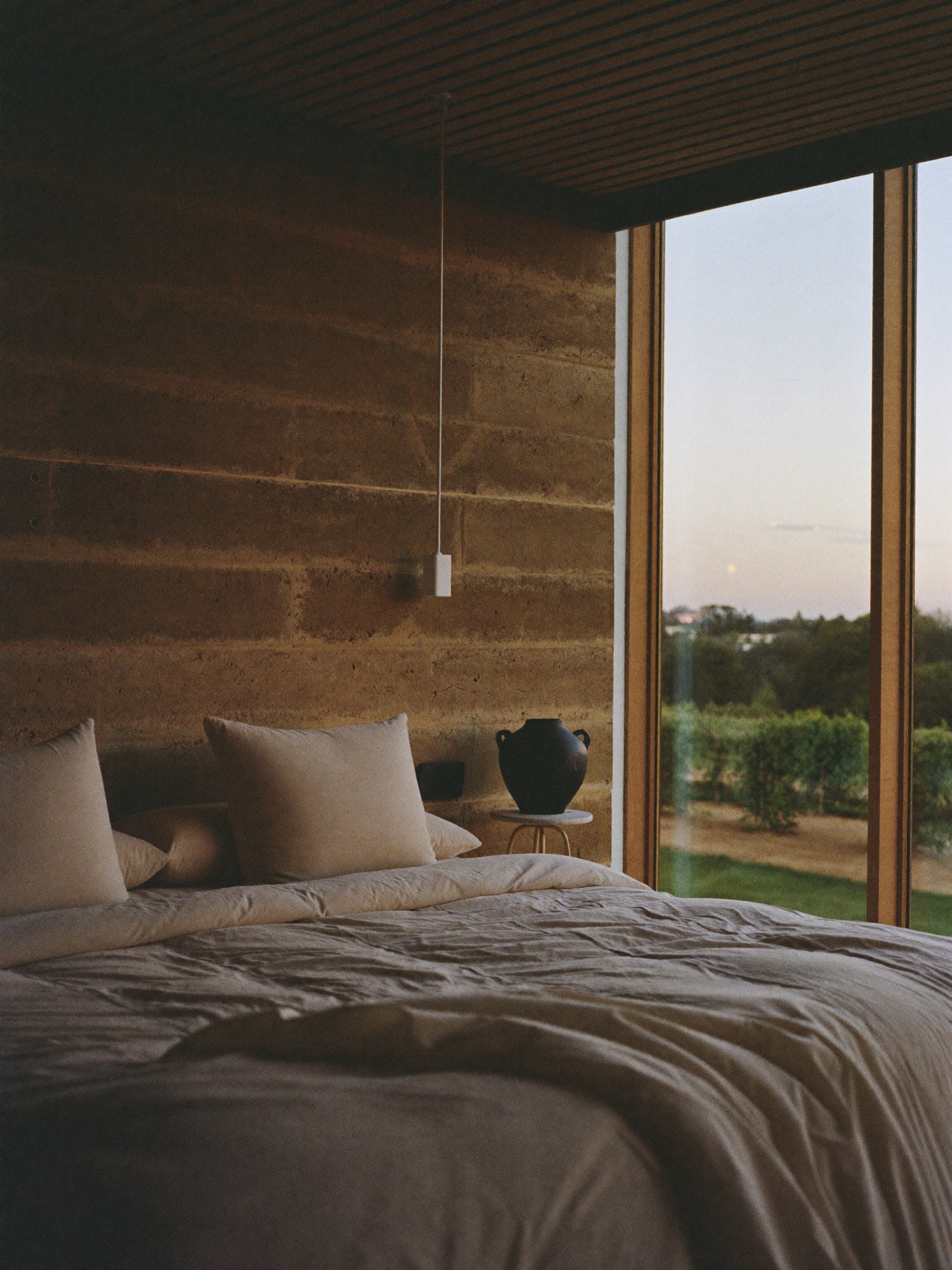 Suite Valle — recámara con muro de tierra y vista al viñedo